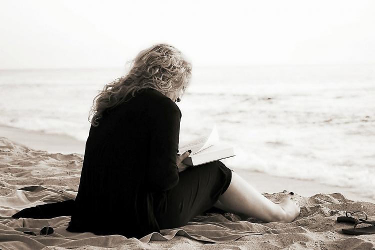 nella foto di Makunin da Pixabay una persona mentre legge in riva al mare